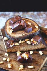 Selective focus. Macro. Chocolate bars with peanuts and caramel. Peanut. Wood background. Sweets, chocolate, nuts.