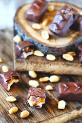 Selective focus. Macro. Chocolate bars with peanuts and caramel. Peanut. Wood background. Sweets, chocolate, nuts.