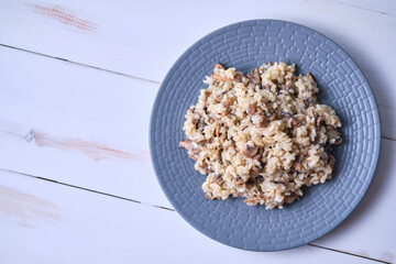 Risotto with mushrooms close-up on a gray plate. Italian dish on a white wooden table.