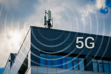 4G, 5G transmitters in an urban environment. Cellular base station with transmitting antennas on the roof of an office building against a cloudy sky