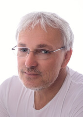 Portrait of European man with glasses and beard, 60 years old, looking at camera with a smile