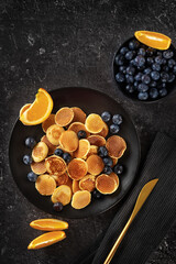 Top view over trendy mini pancakes on black background