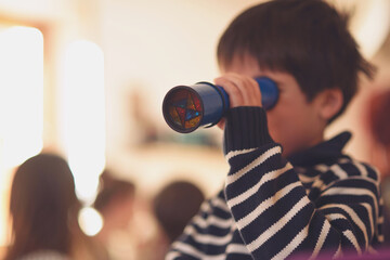 Boy looking through colored kaleidoscope. - obrazy, fototapety, plakaty