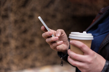 Hand with phone and Cup of coffee close-up. Focus on the phone