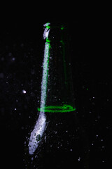 Water splashes crash into a fogged cold bottle of beer on a black background.