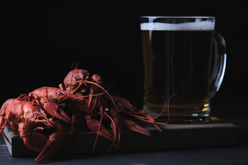 Beer in a glass and red boiled river crayfish on a wooden board. Great beer snack.