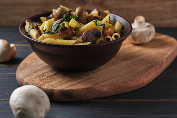 Vegetarian pasta with mushrooms, chickpeas, spinach, spices and herbs. Italian pasta in a bowl on an old wooden table.