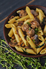 Vegetarian pasta with mushrooms, chickpeas, spinach, spices and herbs. Italian pasta in a bowl on an old wooden table.