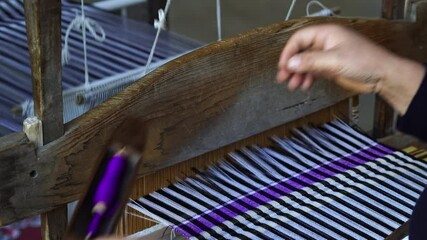 Traditional Vietnamese textile manufacture in craft village where old women work on wooden weaving loom machines and spin yarn creating silk or cotton fabric. Sapa region, North Vietnam, close up