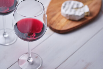 Glass of wine and camembert cheese on a white wooden table. Preparing a romantic dinner.