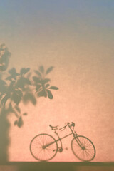 Silhouette of an old bicycle on a dark colored background next to a tree, blurred abstract backdrop