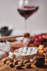 Delicious products for a romantic dinner. Camembert and Parmesan cheese, sausages, nuts, fruits, olives, bread, grapes, wine and honey on an old white wooden table. Top view.
