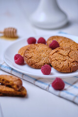 Oatmeal cookies with honey decorated with raspberries. Dessert on a towel, on a white kitchen table close-up.