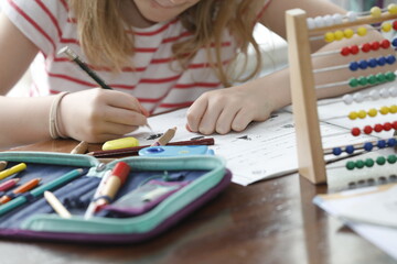 Kleines Mädchen macht Hausaufgaben zuhause am Schreibtisch, mit Mäppchen, rechnen mit Abacus...