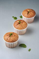 Lemon muffins with poppy seeds, decorated with mint, on the table.