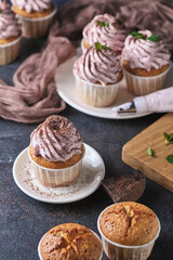 The process of making holiday cupcakes with pink cream. The dessert is decorated with mint leaves and chocolate chips. Background color classic blue.