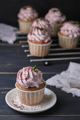 Holiday cupcakes with pink cream. The dessert is decorated with mint leaves and chocolate chips.
