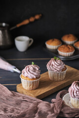 Holiday cupcakes with pink cream. The dessert is decorated with mint leaves and chocolate chips. Cupcakes and coffee. Background color classic blue.