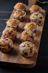 Many cupcakes on a large wooden board. Fresh dessert on a dark old wooden table.