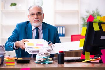 Old employee working in the office in conflicting priorities