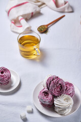Herbal tea with honey and mint and homemade berry zephyr. Delicious and healthy breakfast on a linen tablecloth. Strawberry-currant marshmallows.