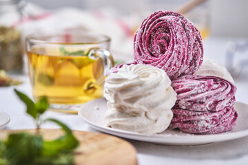 Herbal tea with honey and mint and homemade berry zephyr. Delicious and healthy breakfast on a linen tablecloth. Strawberry-currant marshmallows.