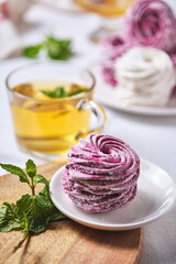 Herbal tea with honey and mint and homemade berry zephyr. Delicious and healthy breakfast on a linen tablecloth. Strawberry-currant marshmallows.