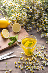 A cup of herbal chamomile tea with camomile blossoms, lemons and mint leaves. The concept of...