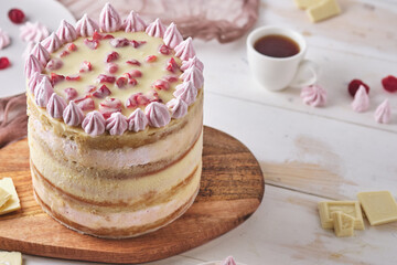 Cake with white chocolate and cherry on a wooden board on a white table. Dessert decorated with homemade marshmallows.