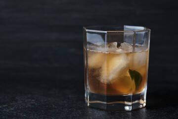 Glass with an alcoholic cocktail on a table in a bar. Whiskey with ice garnished with lime.