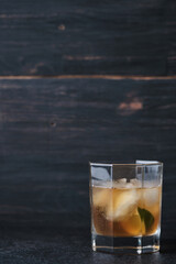 Glass with an alcoholic cocktail on a table in a bar. Whiskey with ice garnished with lime.