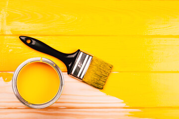 Opened can of paint with brush on yellow freshly painted wooden background. Renovation concept. Vertical photo. - 356263242