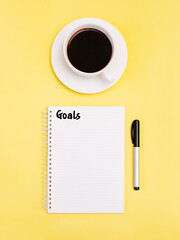 Goals Top view photo Inspirational poster with notebook and cup of black coffee on yellow background