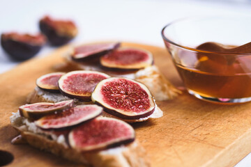 Bruschettas with figs, soft cheese and honey on a wooden board.