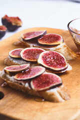 Bruschettas with figs, soft cheese and honey on a wooden board.