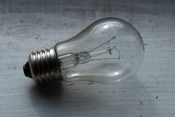 Burned out old light bulb lying on the wooden painted white surface