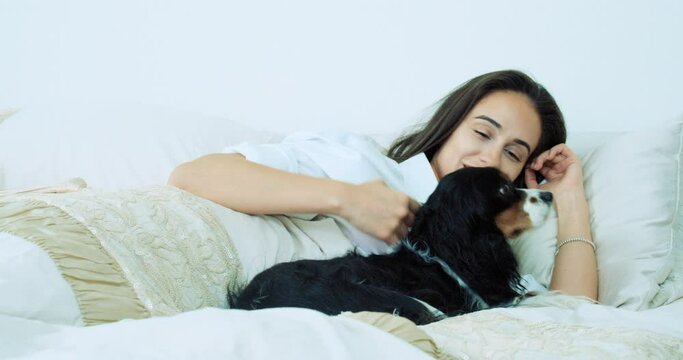 Woman lying with dog in bed