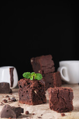 Chocolate brownie with nuts and mint. Sweet and tasty dessert decorated with mint, closeup on a wooden table. Soft focus.