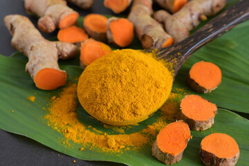 Turmeric powder and turmeric (curcumin) root on black background,For cooking and as herbs