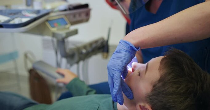 CU R/F Dentists checking boy's (8-9) teeth during appointment and talking to mother / Hove, Sussex, England, United Kingdom