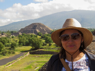 rostro  de joven mexicana con sombrero y gafas  con  las piramides de teotihuacan por detras