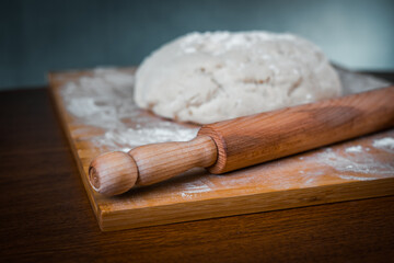 raw dough and rolling pin on a wooden Board in the kitchen