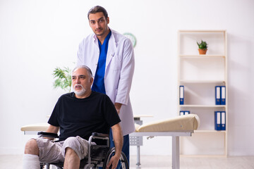 Obraz premium Old injured man visiting young male doctor traumatologist