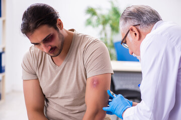Young face injured man visiting experienced male doctor traumato