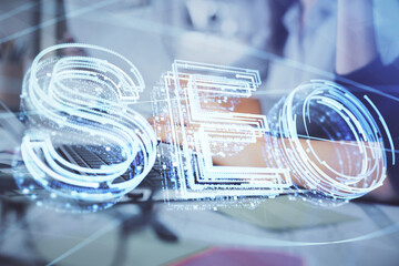 Double exposure of woman hands working on computer and seo hologram drawing. internet search...