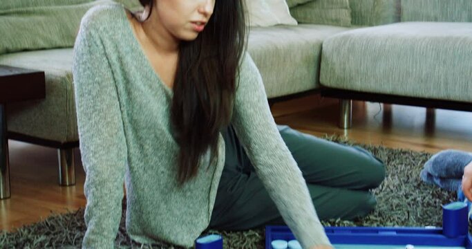 Two women playing backgammon on floor in living room