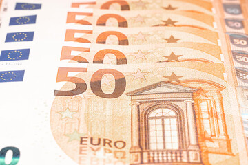 Five 50 euro banknotes stacked up slightly out of focus.