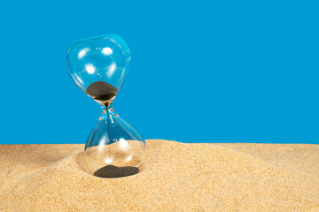 sand timer running in sand with blue background