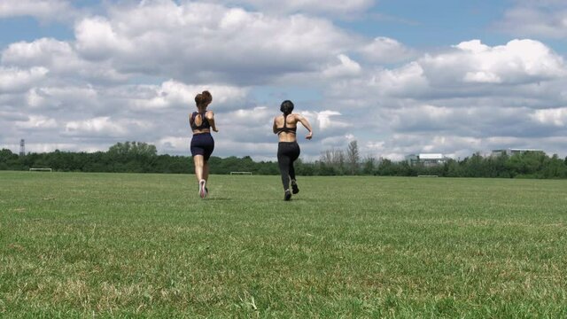 WS Two young women running on grass/ UK