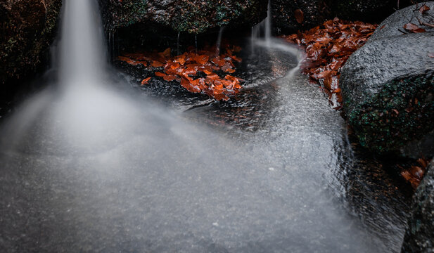 Cascada cayendo entre rocas y hojas de oto&ntilde;o. Agua efecto seda y sensaci&oacute;n de calma